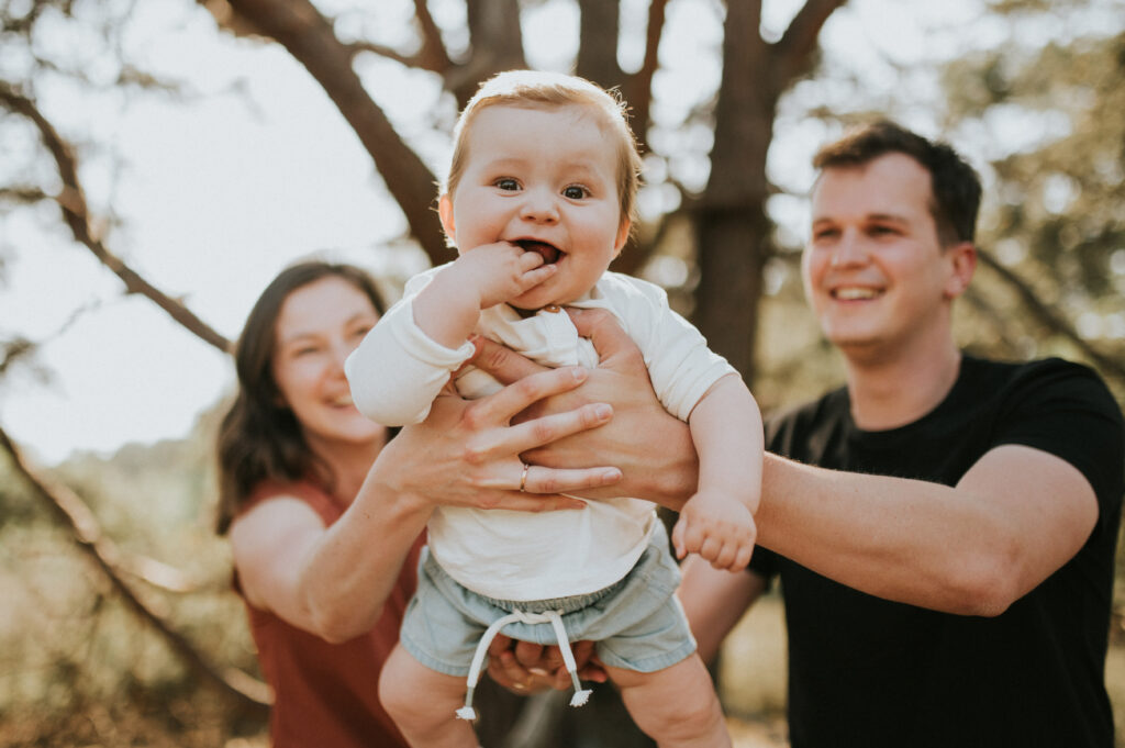 Familiefotografie met gebruik van presets, ouders houden lachend kind vast